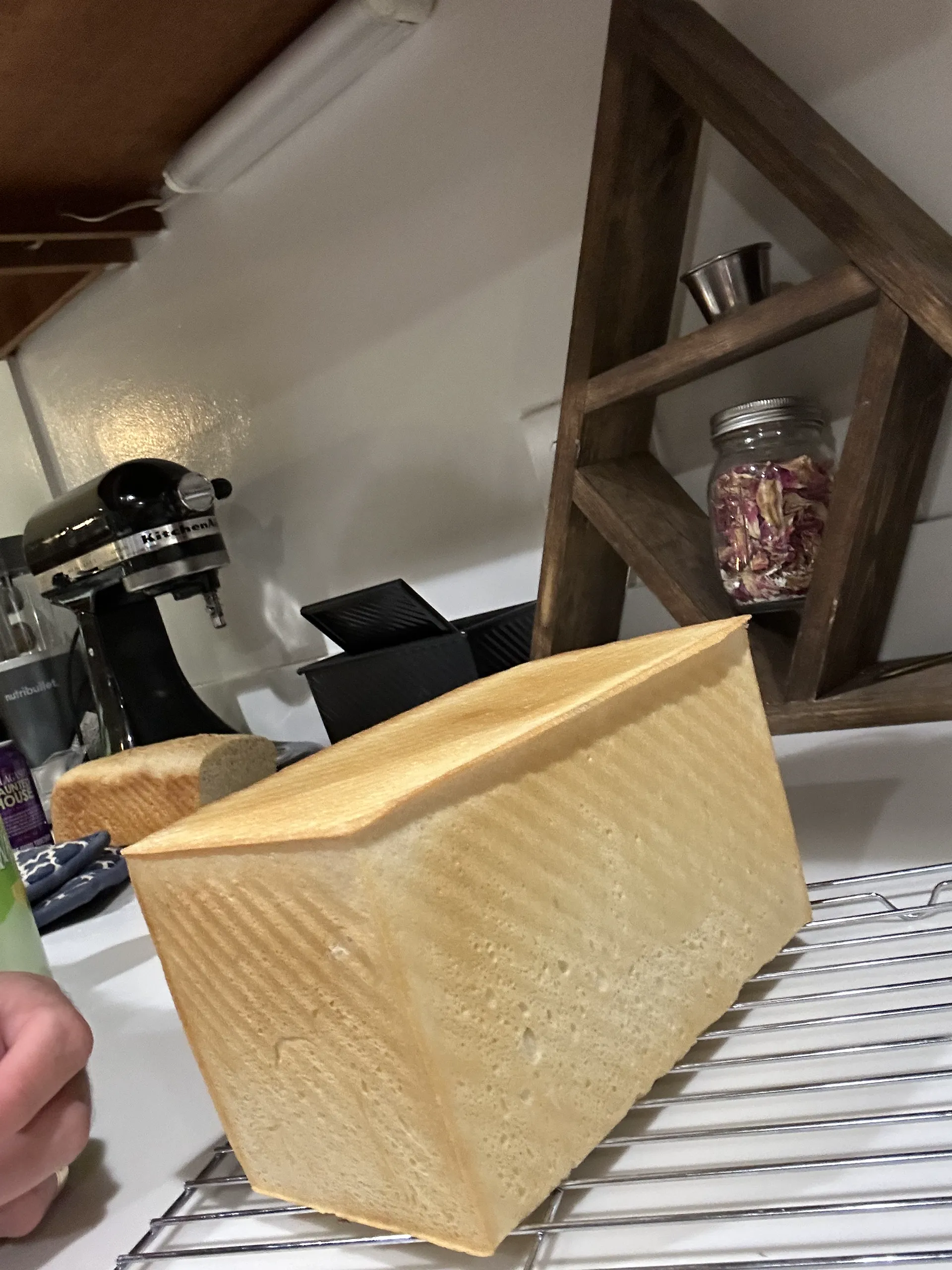 a loaf of sandwich bread cooling on a wire rack
